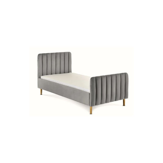A modern single bed frame upholstered in gray velvet with vertical channel tufting on the headboard and footboard, supported by slim gold-toned legs, shown with a white mattress on a plain white background.