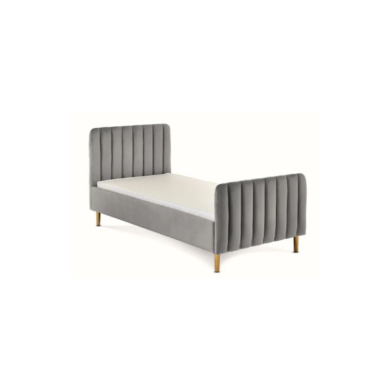 A modern single bed frame upholstered in gray velvet with vertical channel tufting on the headboard and footboard, supported by slim gold-toned legs, shown with a white mattress on a plain white background.