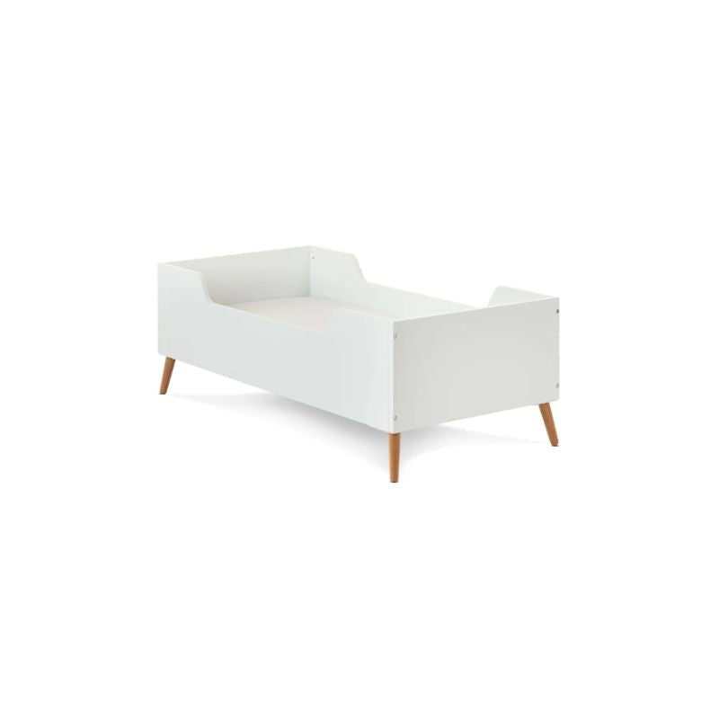 A modern white baby crib with tapered wooden legs, shown from a three-quarter angle on a solid white background.