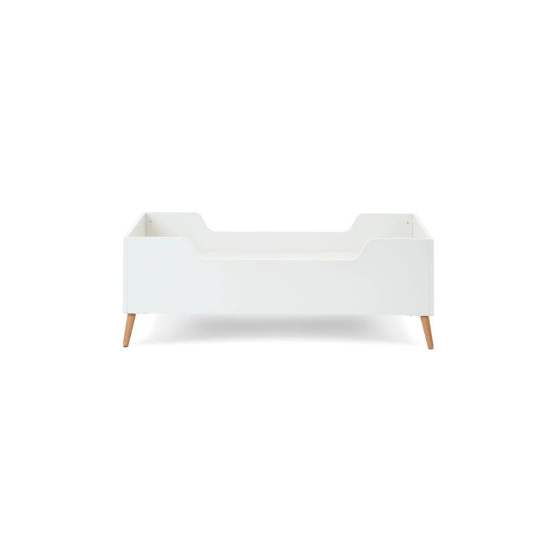 A modern white toddler bed with light natural wood legs, shown from a front-three-quarter angle on a solid white background.