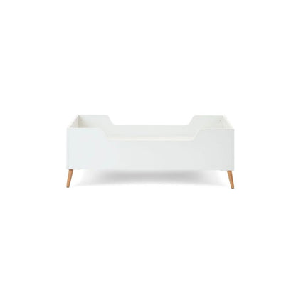 A modern white toddler bed with light natural wood legs, shown from a front-three-quarter angle on a solid white background.