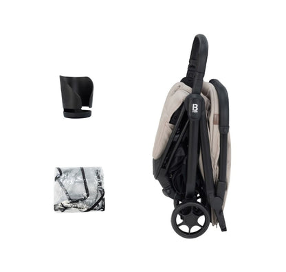 A compact stroller with a light beige (latte) canopy and seat liner, a black frame, and black wheels, shown from a three-quarters angle on a solid white background.