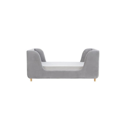 A gray upholstered children's daybed in a styled nursery or playroom with teal paneled walls, a star wall decor piece, a window with bright sunlight, a bean bag, and a basket of toys.