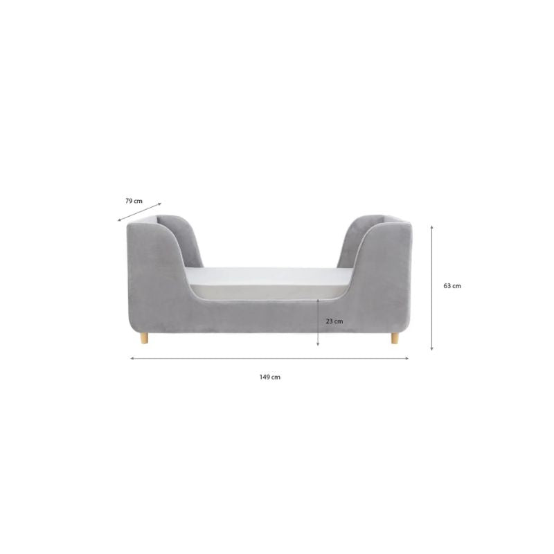 A gray upholstered children's daybed in a styled nursery or playroom with teal paneled walls, a star wall decor piece, a window with bright sunlight, a bean bag, and a basket of toys.
