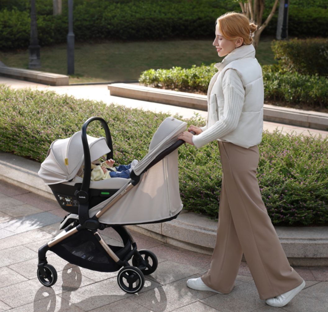 A compact stroller with a light beige canopy and seat, handlebars, and a black frame, shown on a neutral gray background with text at the top reading 'SUITABLE FROM BIRTH TO APPROX. 22KG'.